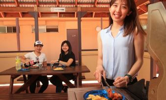 a group of people , including a woman and two men , are gathered around a dining table in a restaurant , enjoying a meal together at Stay at Alice Springs Hotel