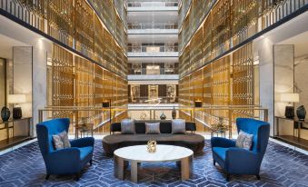 a modern living room with two couches , a coffee table , and a marble floor in front of a tall glass elevator at Waldorf Astoria Kuwait