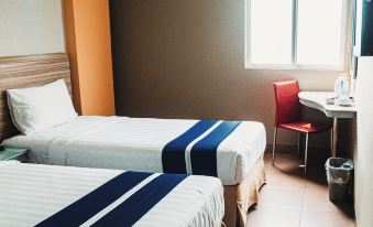 a hotel room with two beds , a window , and a tv , all neatly arranged on wooden nightstands at Metland Hotel Bekasi