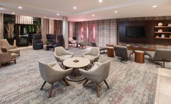 a modern living room with a couch , chairs , and dining table arranged around a large screen tv at Courtyard Pittsburgh Washington/Meadow Lands