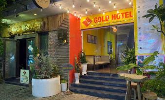 a small hotel with a neon sign above the entrance , surrounded by potted plants and trees at Gold Hotel Hue