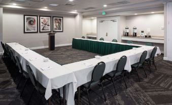a large conference room with multiple tables , chairs , and a green tablecloth set up for a meeting at Hilton Garden Inn Hilton Head