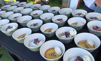 a dining table filled with a variety of bowls containing different types of desserts , such as cakes and ice cream at Glamping with Llamas