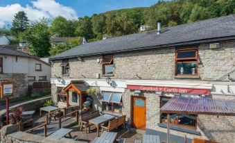 "a stone building with a wooden sign that reads "" the lady 's castle inn "" has several tables and chairs outside" at The Gwaelod y Garth Inn