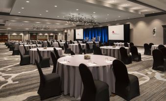a large conference room with round tables and chairs , a stage in the background , and a chandelier hanging from the ceiling at Cleveland Marriott East