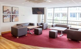 a modern waiting room with several chairs , couches , and tables arranged for guests to sit and relax at Travelodge Slough