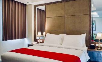 a large bed with a red and white striped blanket is in a hotel room at Horison Gkb Gresik