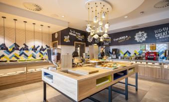 a modern restaurant with a large wooden dining table and a variety of food on display at Hampton by Hilton Stockton on Tees