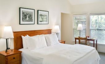 a clean , well - organized bedroom with a wooden bed , white sheets , and two framed pictures on the wall at Southbridge Napa Valley