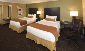 a hotel room with two beds , a desk , and lamps , giving it a cozy and inviting atmosphere at Sterling Inn