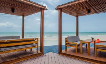 a wooden deck overlooking the ocean , with two lounge chairs placed under a wooden shelter at The Yana Villas Hua Hin