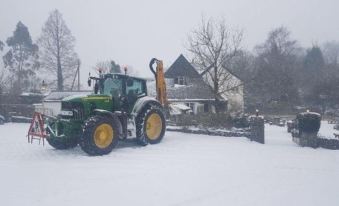 a tractor is parked in a snowy field with a house and trees in the background at The Nobody Inn