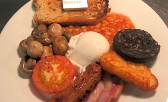 a white plate filled with a variety of food items , including eggs , beans , tomatoes , mushrooms , and other vegetables at The Mortimer Arms