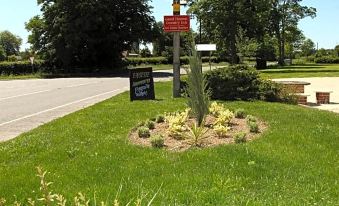 "a sign on a post in the middle of a grassy area near a road , indicating that it is a sign for "" our home """ at The Red Lion