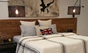 a cozy bedroom with a wooden headboard , a queen - sized bed , and two lamps on either side of the bed at Okoboji Commons Hotel, Trademark Collection by Wyndham