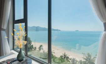 a room with a large window overlooking the ocean , featuring a vase of flowers on a table at Navada Beach Hotel