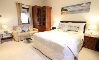 a bedroom with a large bed , a couch , and a tv . also a chair in the room at Chale Bay Farm