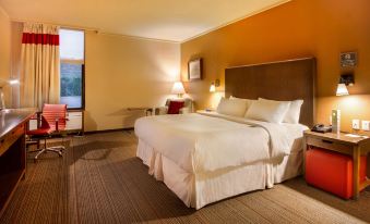 a large bed with white linens is in a room with orange walls and brown carpeting at Four Points by Sheraton Saltillo
