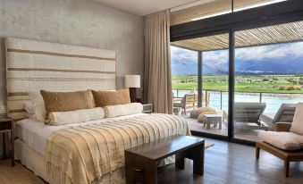 a bedroom with a large bed and sliding glass doors leading to a balcony overlooking mountains at The Vines Resort & Spa