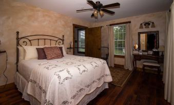 a spacious bedroom with a large bed , a ceiling fan , and a door leading to a patio at The Old Lantern Inn and Barn
