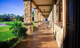 a long , covered walkway with stone walls and a variety of potted plants , creating a serene and inviting atmosphere at Grand Caporal Hotel