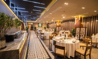 a large dining room with white tables and chairs , some of which are covered in tablecloths at Purple Lotus Hotel