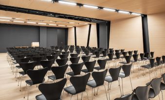a conference room with rows of black chairs arranged in a semicircle , and a podium at the front of the room at Briig Boutique Hotel