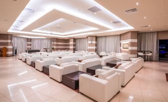 a large room with multiple white couches and chairs arranged in rows , creating a comfortable seating area at Konstantinos Palace