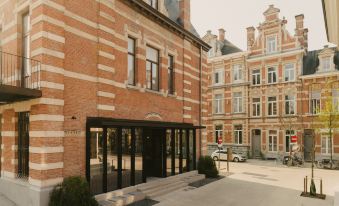 a brick building with a large window and black doors is shown in the courtyard of a brick building at August