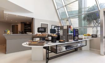 a large , modern coffee shop with a variety of food and drinks on display , including donuts , cakes , and beverages at B&B Hotel Trapani Crystal