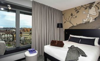 a modern bedroom with a large window , grey curtains , and a bed decorated with black and white patterns at Ibis Styles Geneve Carouge