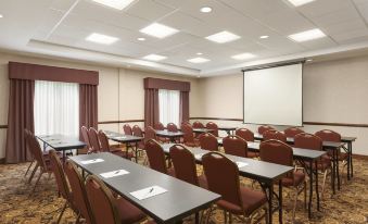 a large conference room with multiple tables and chairs , a projector screen , and curtains , ready for a meeting or presentation at Country Inn & Suites by Radisson, Princeton, WV