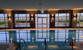an indoor swimming pool with a long , narrow shape and large windows on one side at The Golden Jubilee Hotel