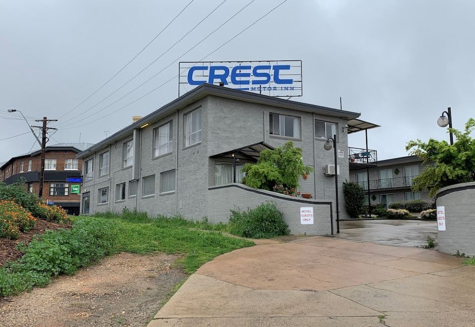 a building with a large blue sign on the side , possibly advertising a hotel or motel at Crest Motor Inn