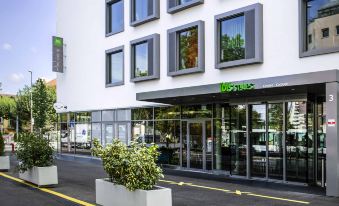 "a large white building with a sign that reads "" mercure "" and an outdoor parking lot in front of it" at Ibis Styles Geneve Carouge