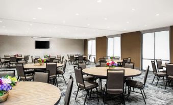 a large dining room with multiple round tables and chairs arranged for a group of people to enjoy a meal together at Home2 Suites by Hilton Long Island Brookhaven