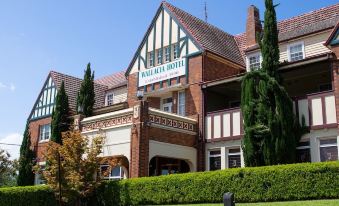 "a large , red brick building with a sign that reads "" nottliffe hotel "" on the side , surrounded by greenery" at Wallacia Hotel