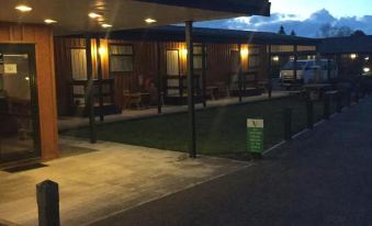a small motel with a green lawn and several chairs , lit by lights at night at Waiouru Welcome Inn