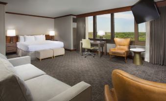 a modern hotel room with large windows , a bed , chairs , and other amenities , including a dining table and chairs at DoubleTree by Hilton Chicago - Oak Brook