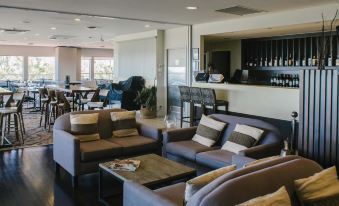 a modern lounge area with several couches and chairs , as well as a bar area at Mercure Clear Mountain Lodge