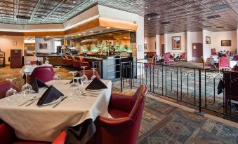 a restaurant with a bar and dining area , featuring red chairs and white tablecloths on the tables at Squire Resort at The Grand Canyon, BW Signature Collection