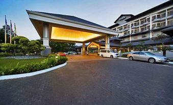 a hotel entrance with a large covered walkway and several cars parked in front of it at Thistle Port Dickson Resort