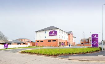 "a large building with a purple sign that says "" premier inn "" is surrounded by green grass and trees" at Premier Inn Melton Mowbray