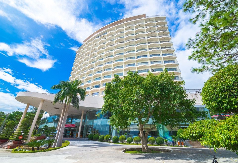 a modern hotel with multiple floors , surrounded by trees and other buildings , under a clear blue sky at Sai Gon Ha Long Hotel