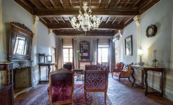 a spacious room with wooden beams on the ceiling , two chairs , a chandelier , and a dining table at Palazzo Leopoldo Dimora Storica & Spa