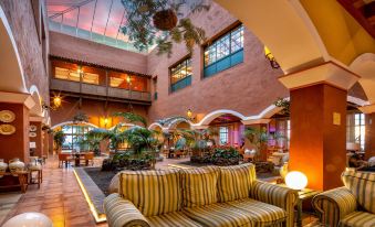 a cozy indoor area with a couch , chairs , and potted plants in front of large windows at La Palma Princess