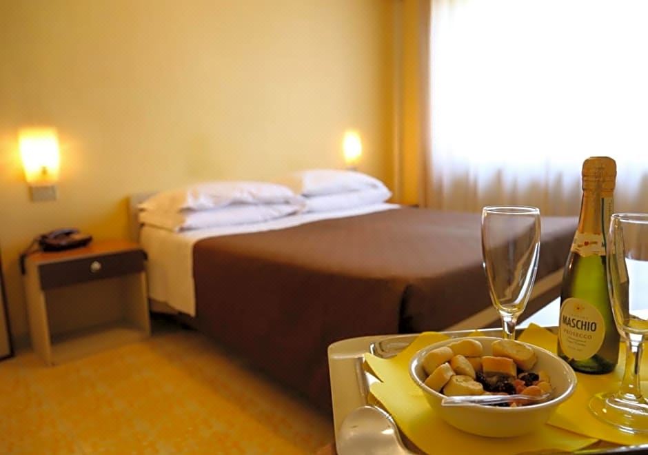 a bed with a tray of food next to it , and a glass of wine placed on the tray at Hotel Sole