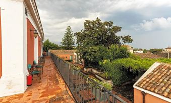 a rooftop terrace with a red brick floor , potted plants , and a view of trees and buildings at Etna Hotel