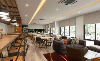 a modern , spacious living room with wooden floors and large windows , featuring comfortable seating arrangements and a dining area at Fortune Hotel Buriram