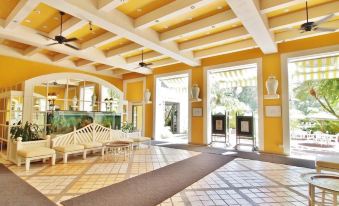 There is a spacious room with chairs and tables positioned in the center, adjacent to an open doorway at Regency Art Hotel